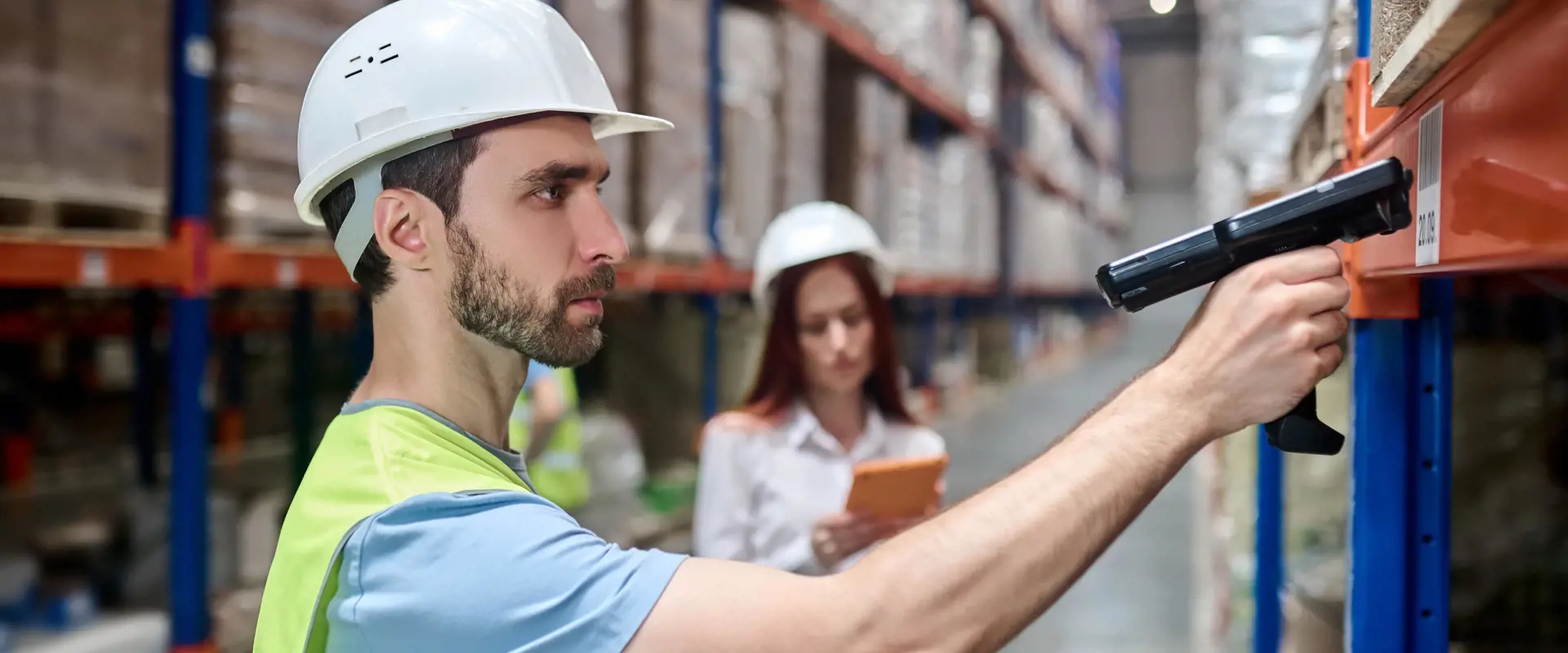 RFID RTLS Uomo Che Scansiona Il Codice A Barre Dal Carico E Donna Con Il Tablet Min